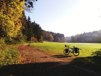 Bicycle on field by trees against sky