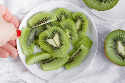 Close-up of hand holding kiwi plate at table