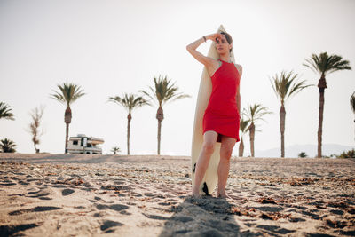 Woman with palm trees on beach against clear sky