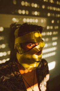 Close-up portrait of young man covering face with tape while standing against wall