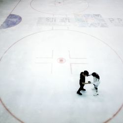 High angle view of man and woman ice-skating on rink