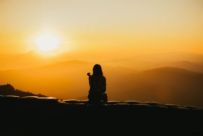 Silhouette man standing on mountain against sky during sunset