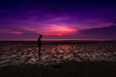 Silhouette person standing on beach against sky during sunset