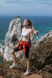 Full length of woman on rock at sea shore
