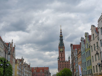 Low angle view of buildings in city against cloudy sky