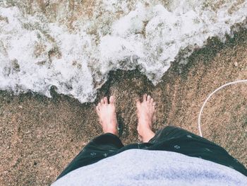 Low section of person standing on sand at beach