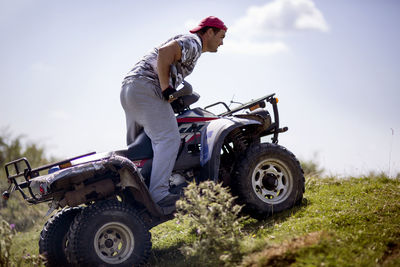 Side view of man riding quadbike against sky