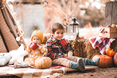 Cute baby girl with kid boy drinking hot tea with autumn decor outdoors. good morning.