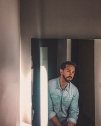 Portrait of man standing against wall at home