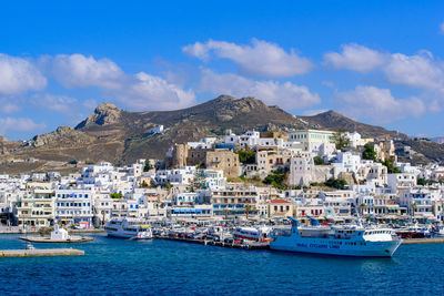 Sailboats in sea by city buildings against sky