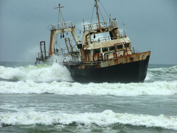 Abandoned ship in sea against sky