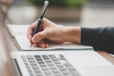 Midsection of woman using laptop on table