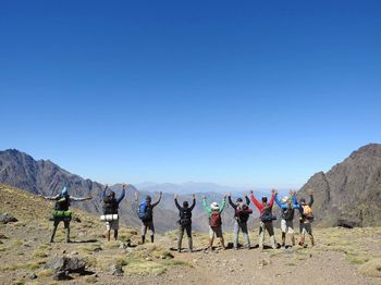 Group of people on desert against clear blue sky