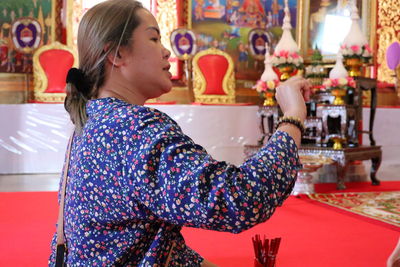 Side view of woman praying in temple