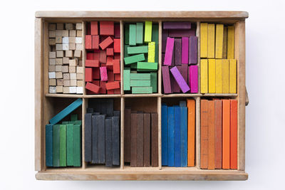 Directly above shot of colorful wooden blocks in container on white background