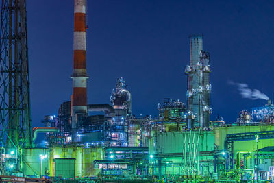 Low angle view of illuminated factory against sky at night