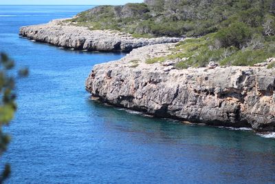 Scenic view of sea by cliff against sky