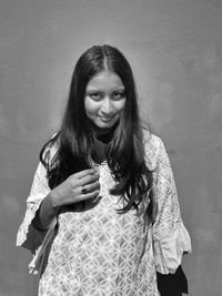 Portrait of smiling woman standing against wall