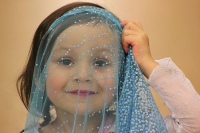 Close-up of cute girl holding net over face