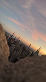 Aerial view of crane by building against sky during sunset