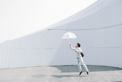 Full length of man holding umbrella against wall