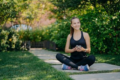 Portrait of young woman sitting on plant