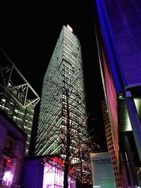 Low angle view of illuminated skyscraper against sky at night