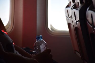 Midsection of woman with water bottle sitting in airplane