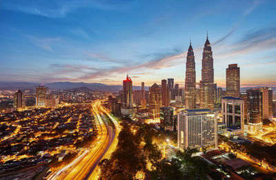 Illuminated cityscape against sky during sunset