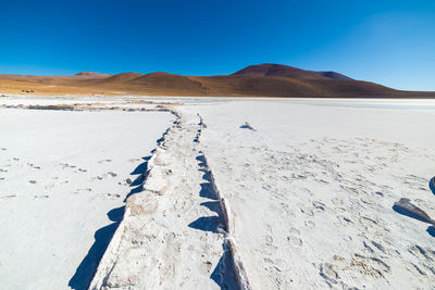 Scenic view of desert against clear blue sky