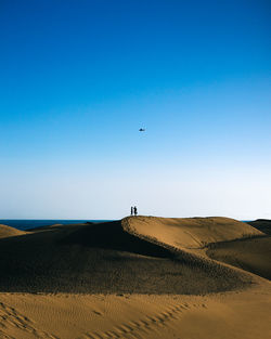 People on top of a hill of a dunes close to the sea