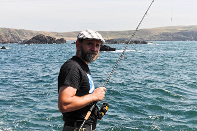 Side view portrait of bearded mature man fishing in sea