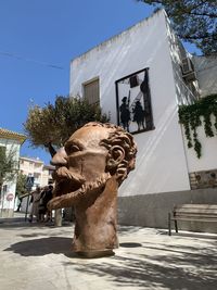 Statue by street against buildings in city against clear sky