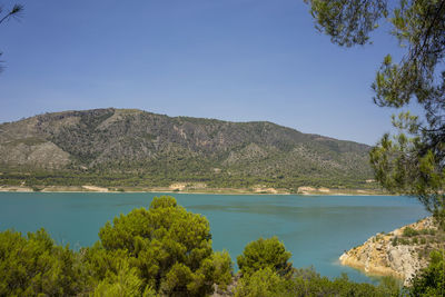 Scenic view of lake and mountains against clear blue sky