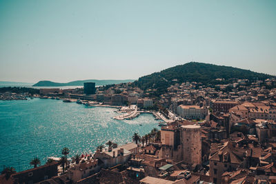 High angle view of town by sea against clear sky