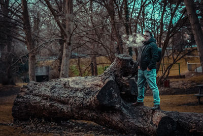 Side view of man standing on rock in forest