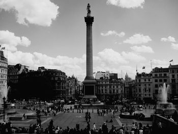 People at trafalgar square in city against sky