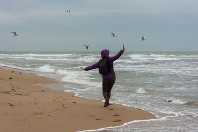 Young woman beach seagulls. cinematic neutral winter plot. a happy woman walks along a sandy beach