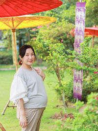 Portrait pregnant woman traveling in the outdoor park red umbrella background 