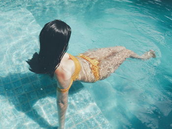 Rear view of woman swimming in pool