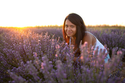 Young  woman looks at camera among lavender flowers at sunset