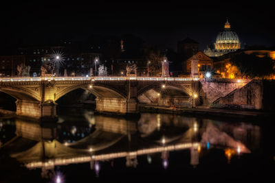 Illuminated bridge over river at night