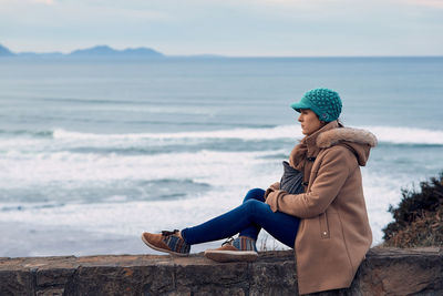 Full length of young woman sitting on beach