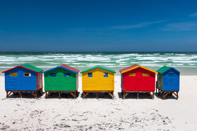 Beach huts against sea against blue sky