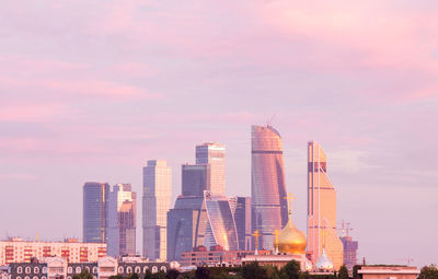 Modern buildings in city against sky during sunset