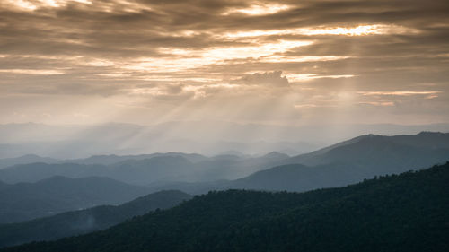 Scenic view of mountains against cloudy sky during sunset