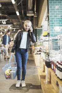 Girl using smart phone while standing in organic groceries store