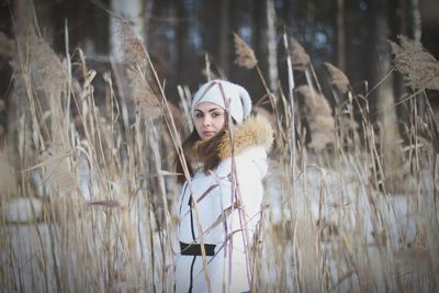 Portrait of woman standing by plants during winter