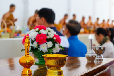 Religious offerings on table by people and monks praying in temple