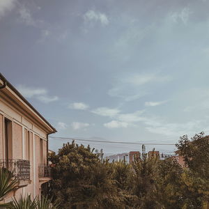 Houses and trees by sea against sky